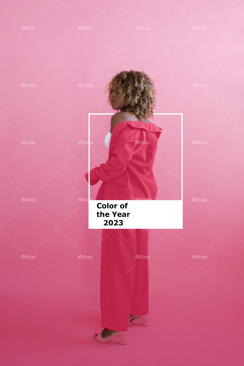 Pantone 2023 Viva Magenta. New trend color. African American woman in color of the year costume on a plain background in the studio. Color of the Year 2023 according to the Institute of Color