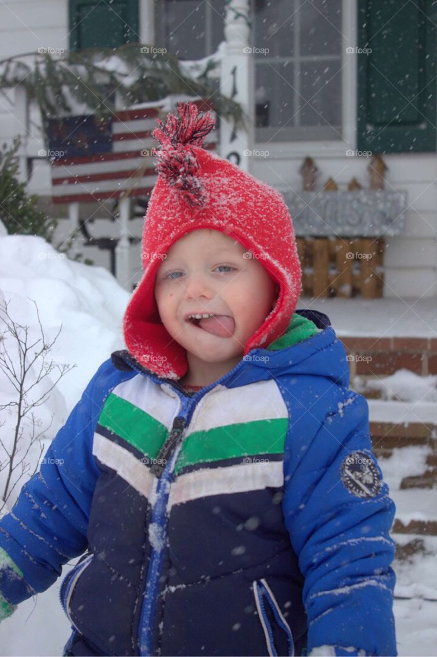 Boy sticking out tongue in snow