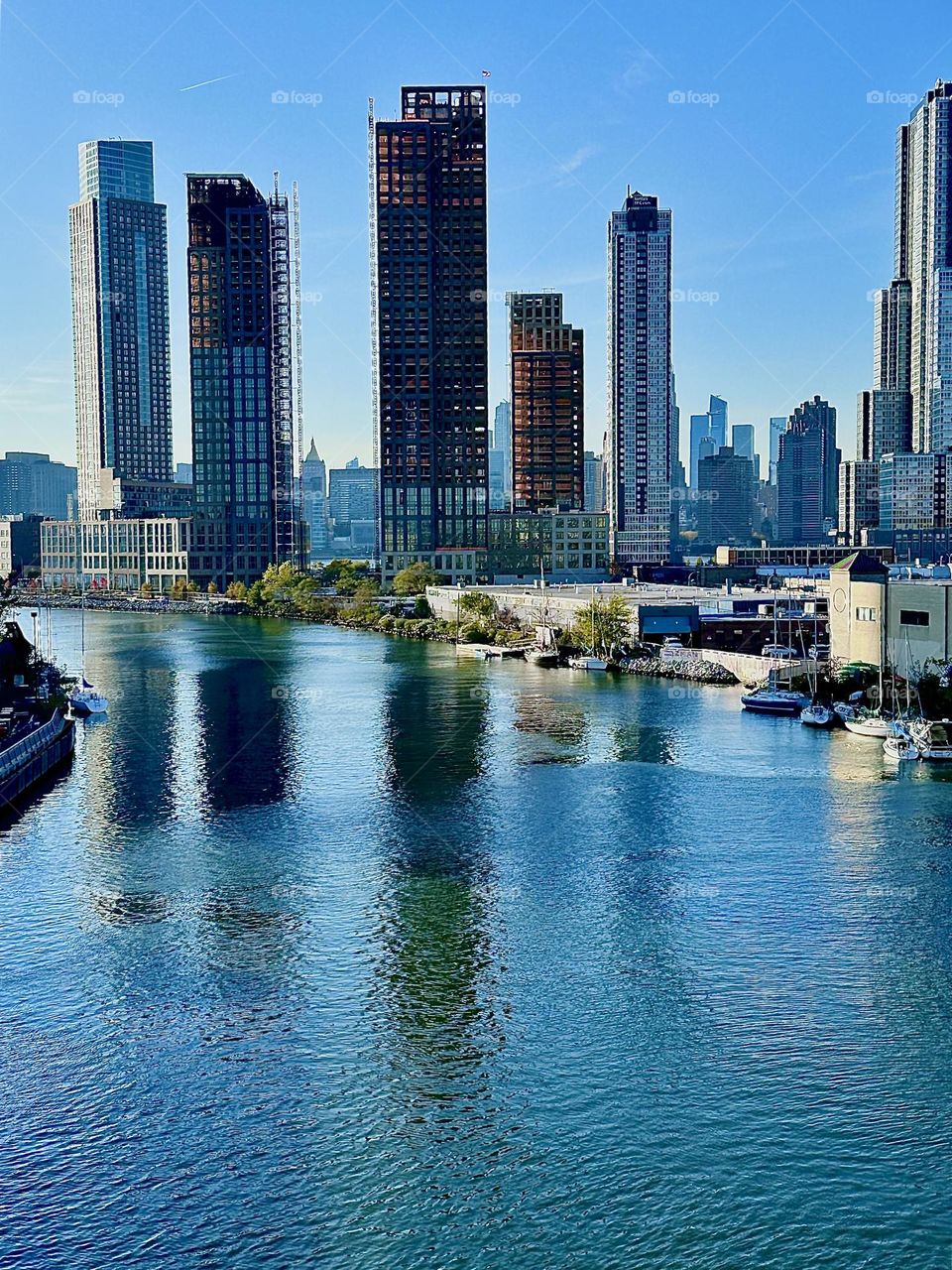 This is “Newtown Creek”, an ocean inlet of the “East River” seen from the “Pulaski Bridge” that connects “Greenpoint”, Brooklyn to LIC, Queens. Straight ahead in the distance you can see “Manhattan”. 2023. Hypnotic Productions
