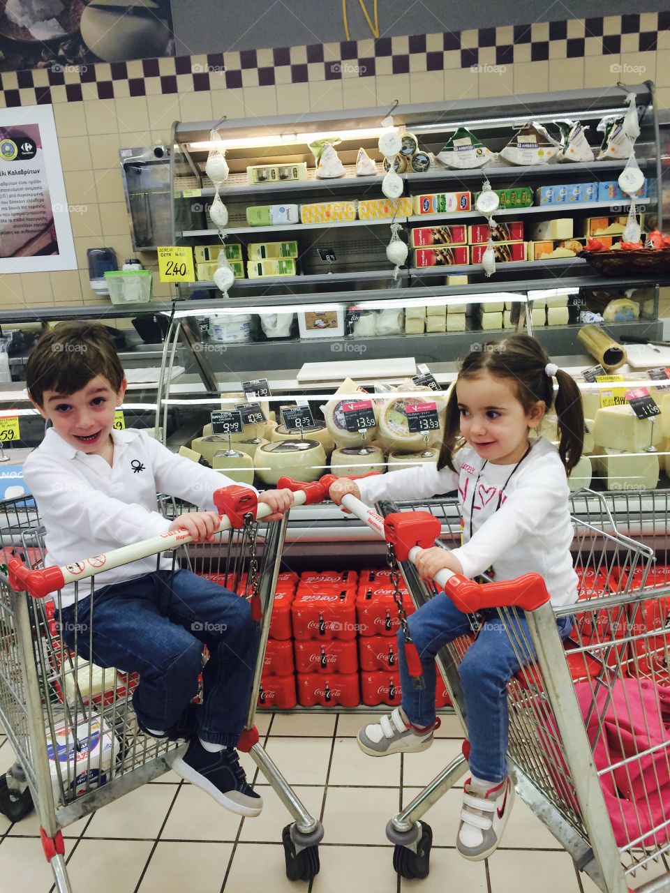 Children sitting on shopping cart in mall