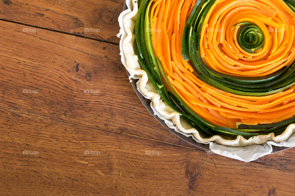 A colourful savoury tart in the making with sliced carrots and sliced courgettes/zucchini