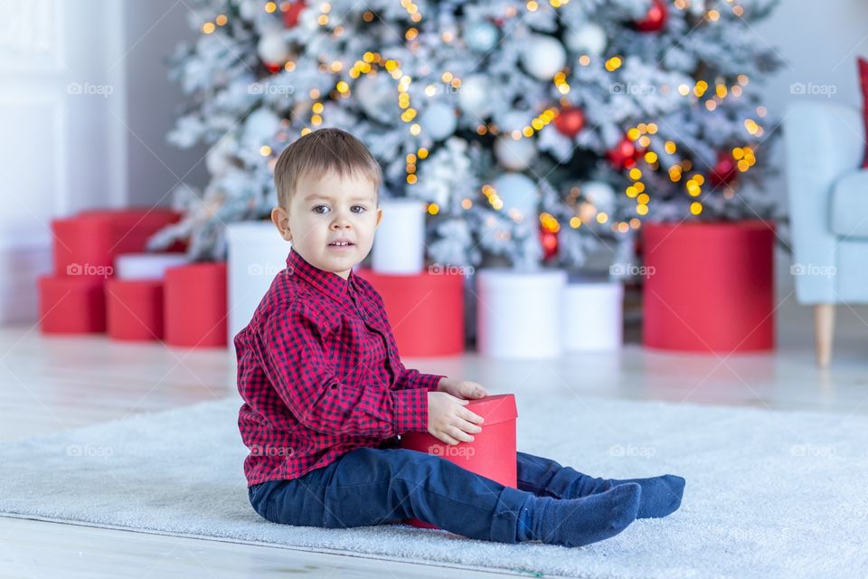 boy and gift box next to christmas tree