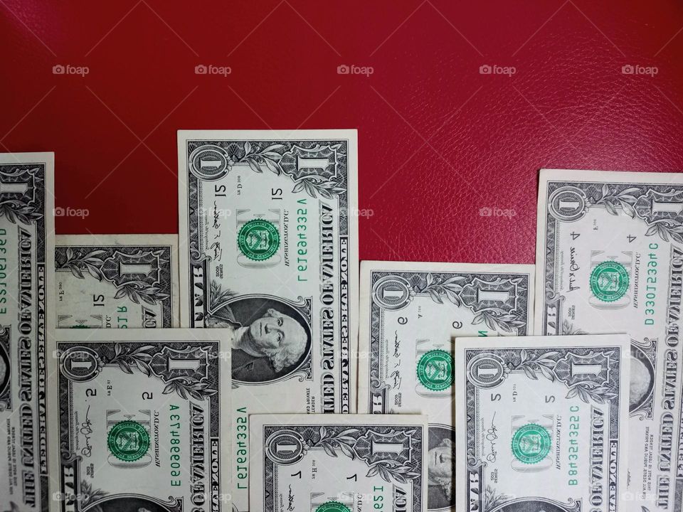 spread out dollar bills on a red background.