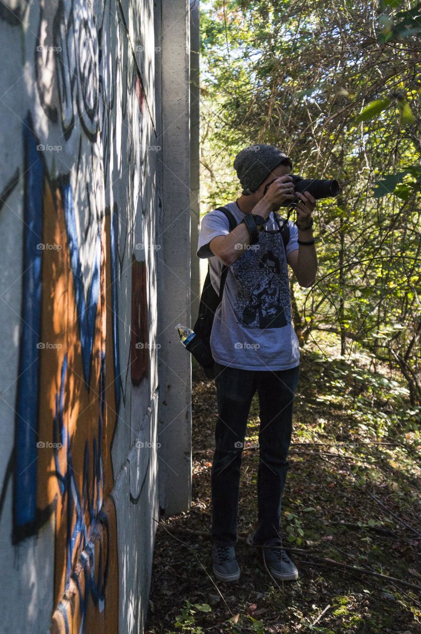 A young man photographs deep in the woods