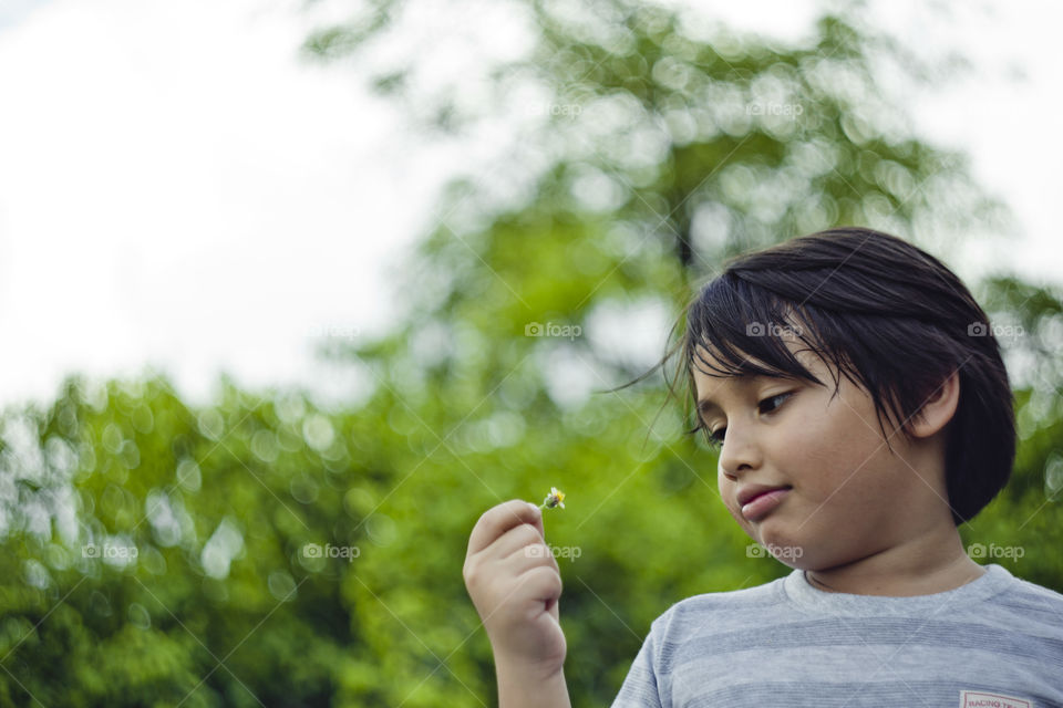 outdoor portrait of happy young eurasian boy on a blurry out of focus bokeh foliage background