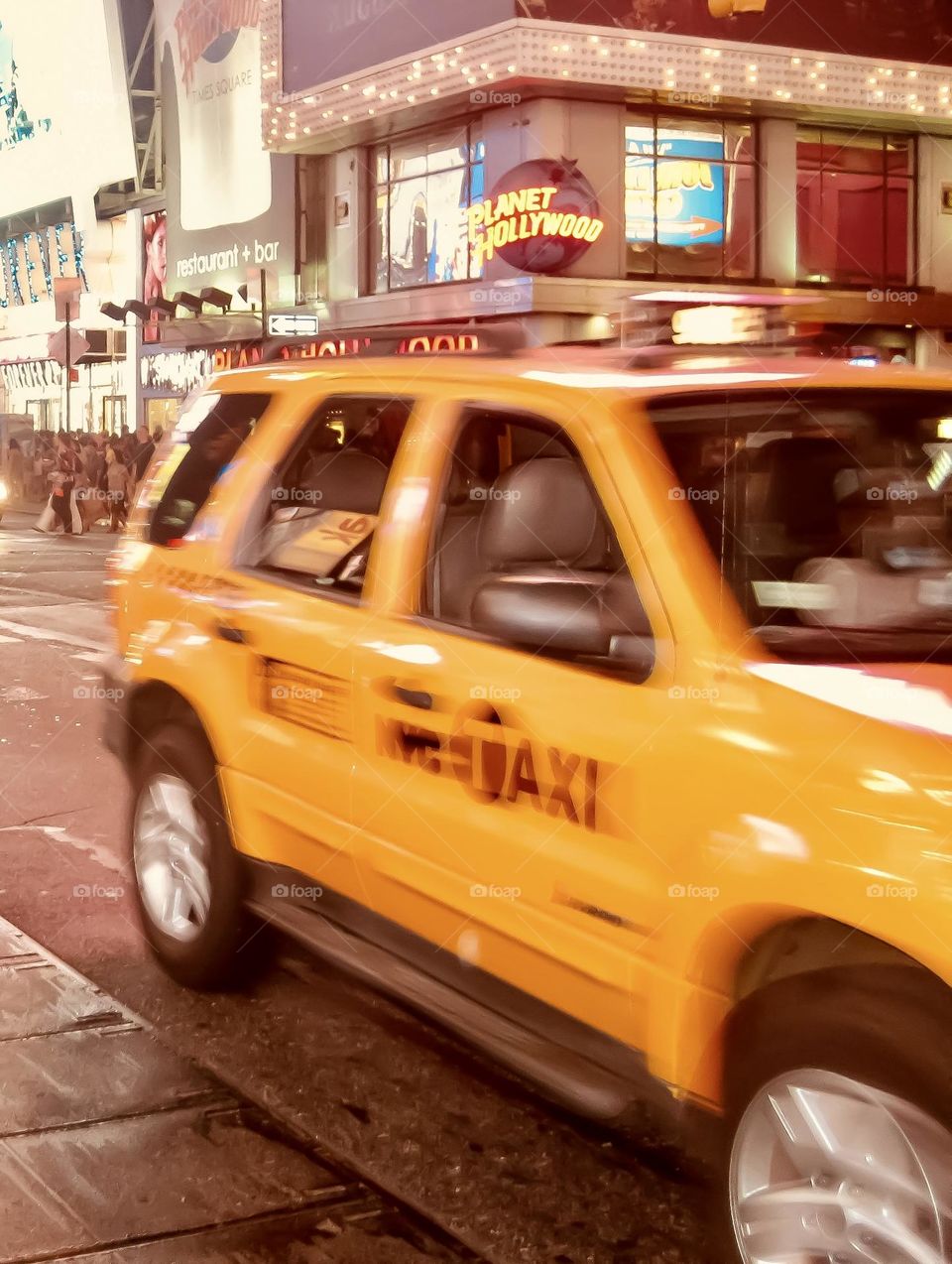 A classic New York City yellow flies by near Times Square.