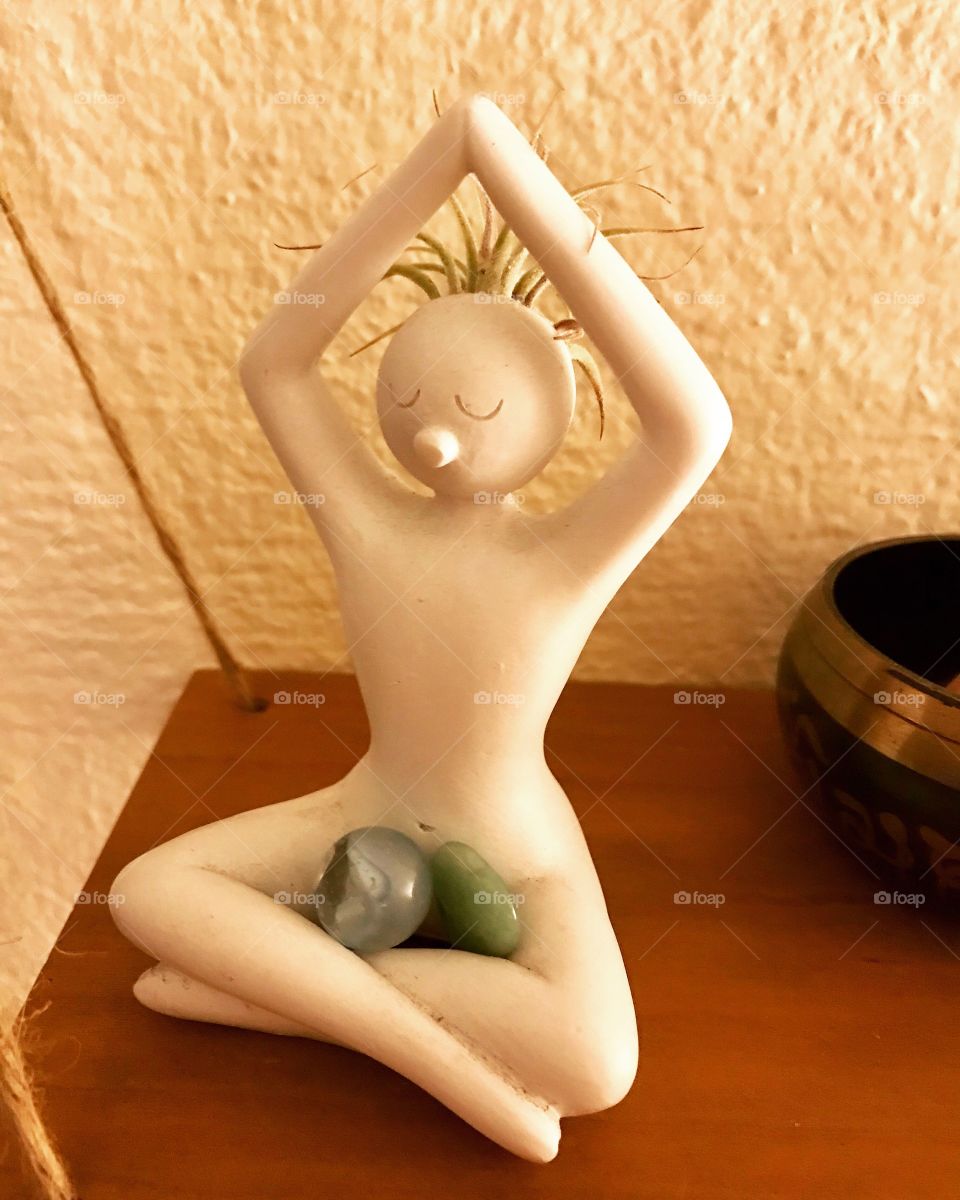 White yoga meditating statue with green air plant hair and crystals in lap
