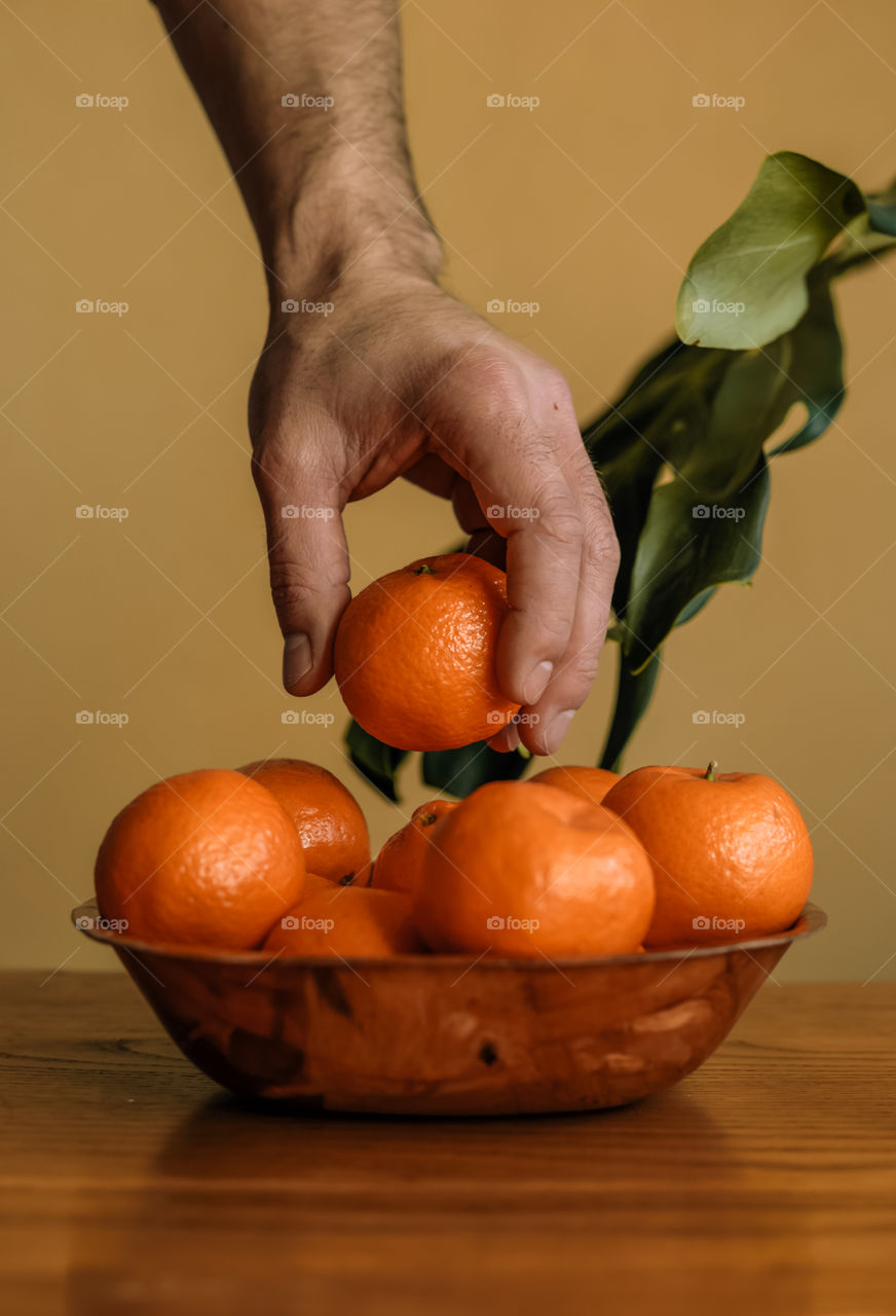 Close-up of hand picking tangerine fruits from table