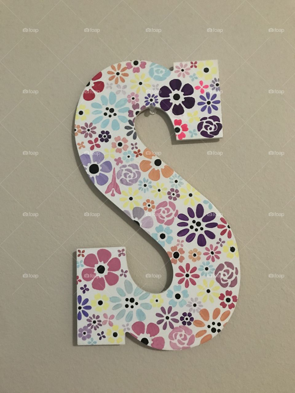 Cute painted s monogrammed sign covered with acrylic flowers on a white background 