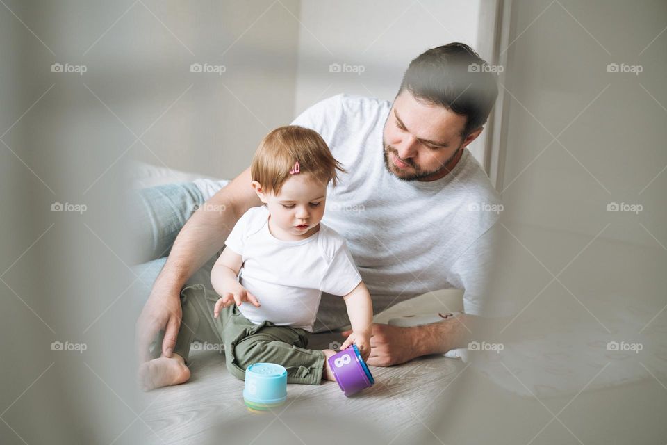 Happy father young man and baby girl little daughter having fun playing with toy in children room at home