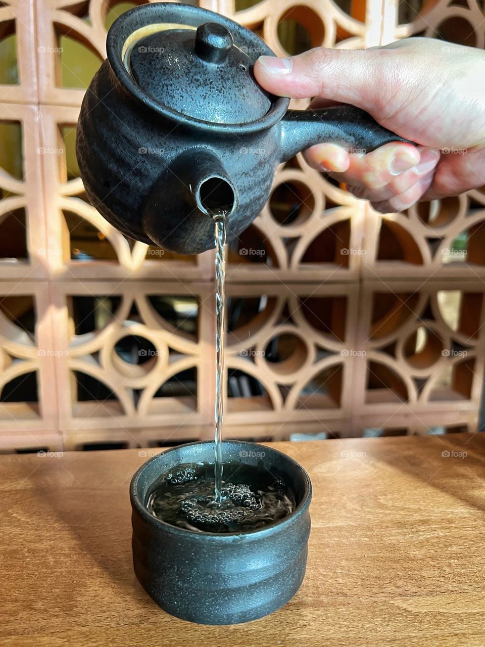 Pouring hot tea into a cup.