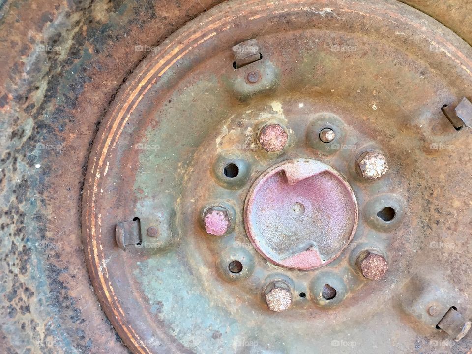 Closeup of a rusted rim and lug bolts on a vintage vehicle