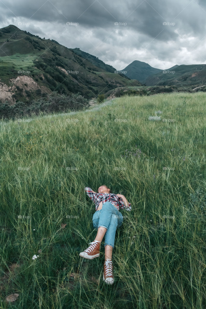 Green relax in mountain. Young woman having a rest on the meadow in mountains