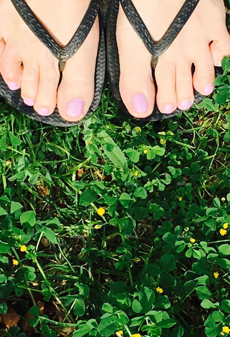 View of bare feet in sandals top down on grass, making a decision to carry on