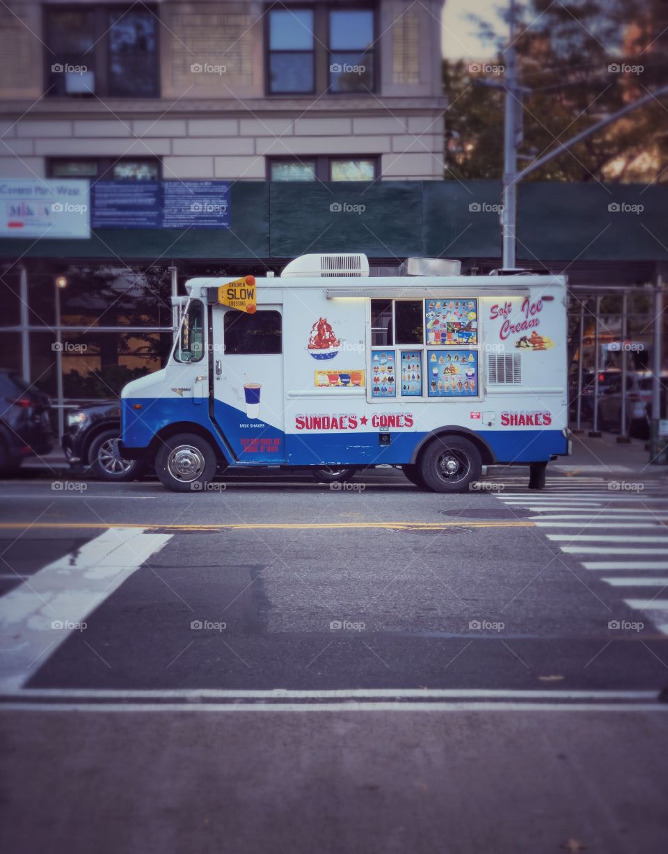 Ice cream truck or van in the street with scaffolding and building background New York city. 