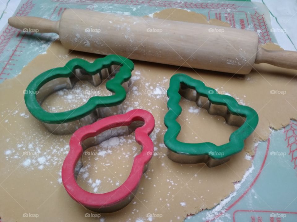 Cut out Christmas cookies with a rolling pins, dough and cutters.