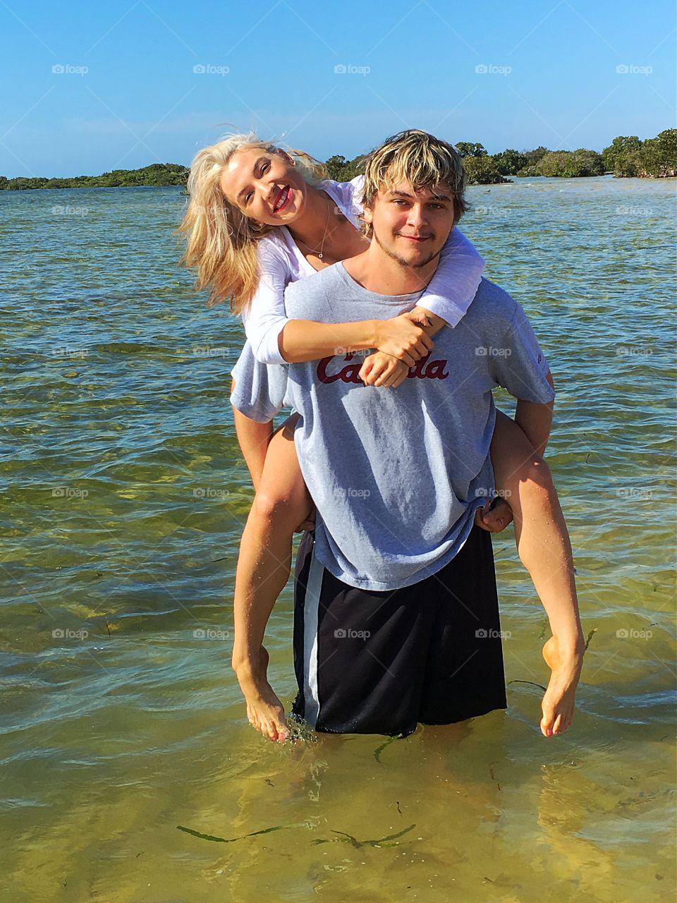 Young couple piggybacking in ocean