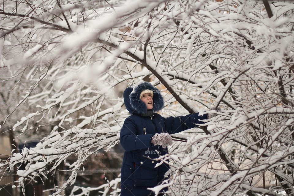 Girl about to shake the bush with snow in winter