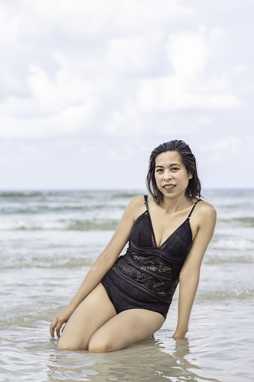 Portrait of Asian woman wearing a swimsuit background sea and sky