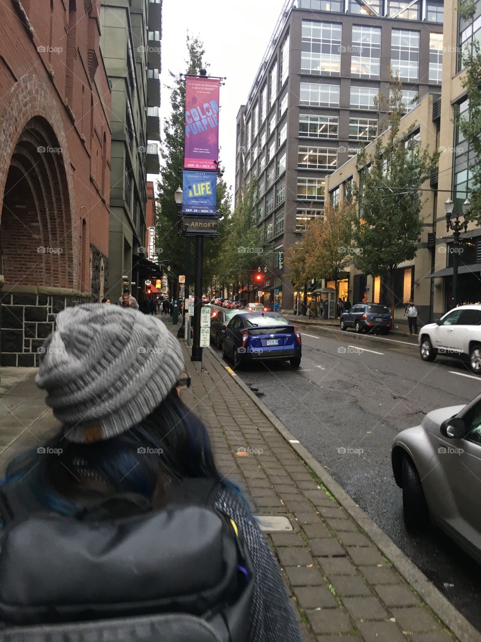 Hipster girl with blue hair walking down sidewalk in Portland Oregon on a cloudy, rainy day 