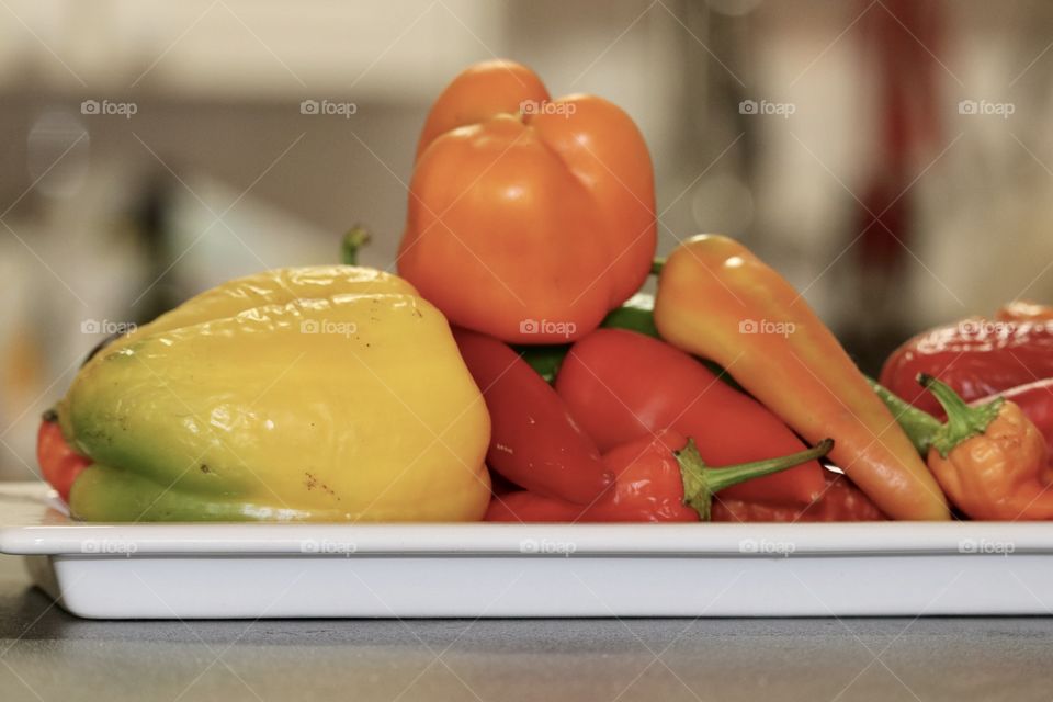 Still life orange sweet bell peppers capsicum atop variety of multi coloured peppers