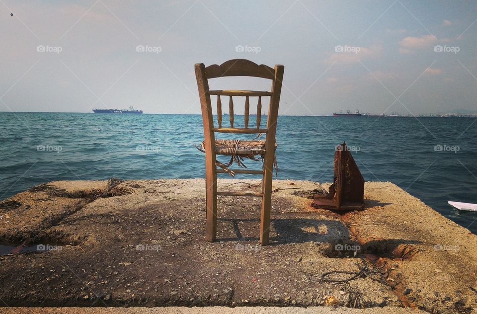 An old chair neglected by the sea in the port of Thessaloniki-Greece.
