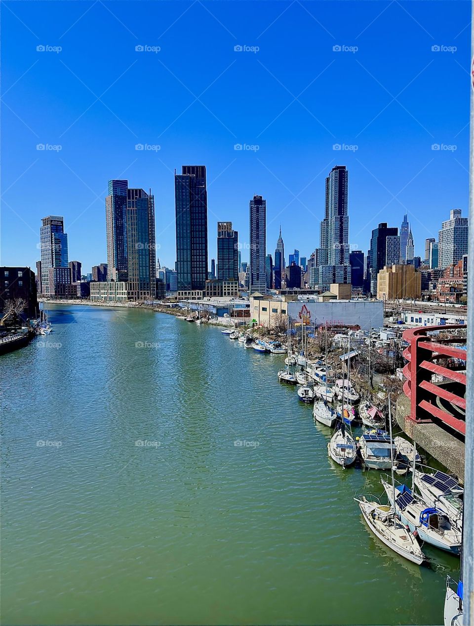 This is “Newtown Creek”, an ocean inlet of the “East River” seen from the “Pulaski Bridge” that connects LIC, Queens to “Greenpoint”, Brooklyn. In the far distance we can see “Manhattan”. 2024. Hypnotic Productions