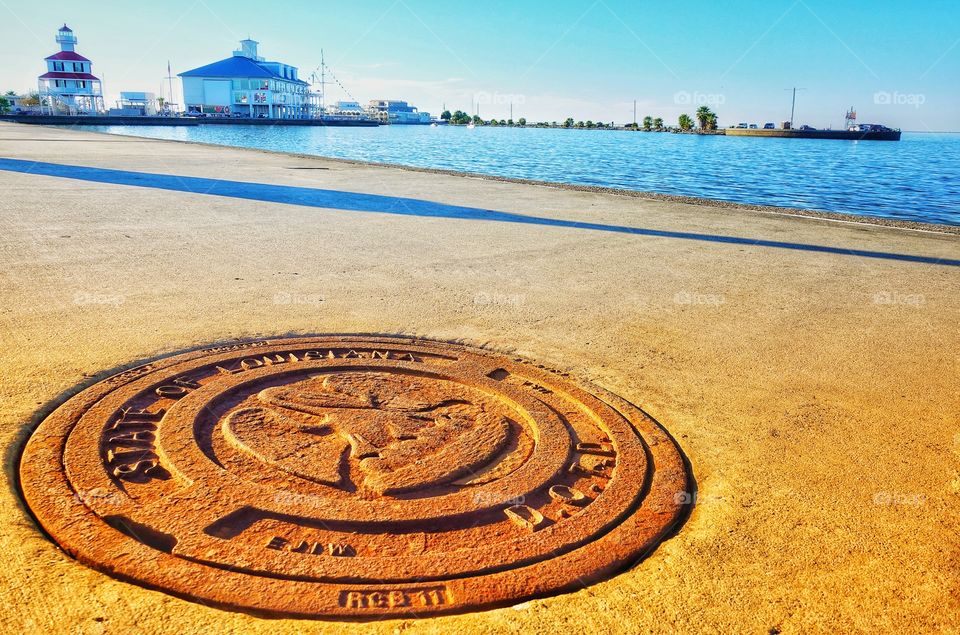 Rusty cast iron footpath drain plate. Along the pedestrian walkway of Lake Pontchartrain, New Orleans, USA.