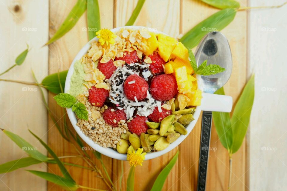 Fresh fruit smoothie bowl - raspberry,  nuts, mangoes,  cereal, seeds, mints