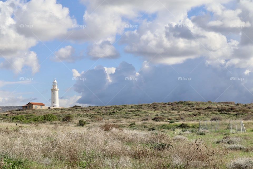 Lighthouse in a meadow with cloudy sky