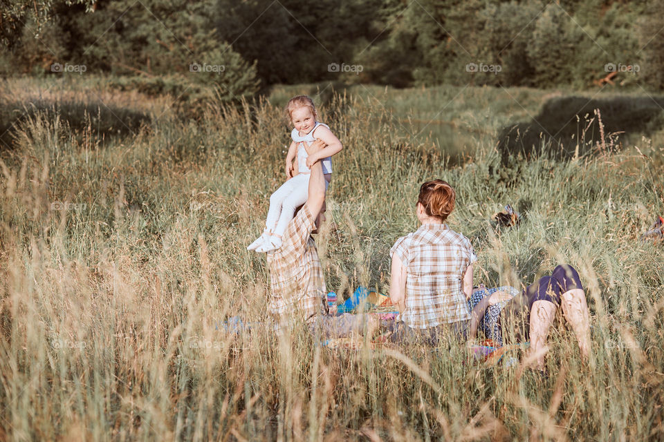 Family spending time together on a meadow, close to nature. Parents and children sitting and playing on a blanket on grass. Candid people, real moments, authentic situations