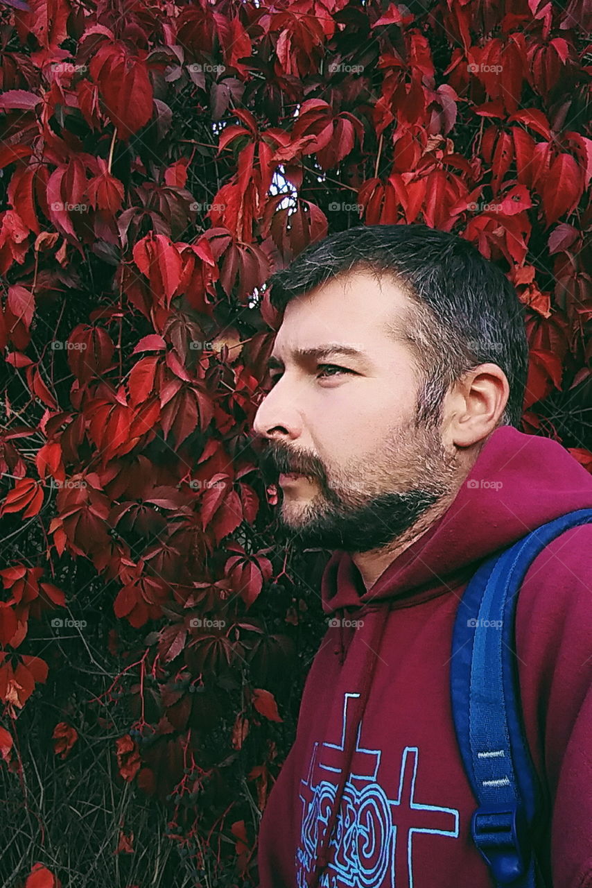 a man with a beard against the backdrop of autumn leaves