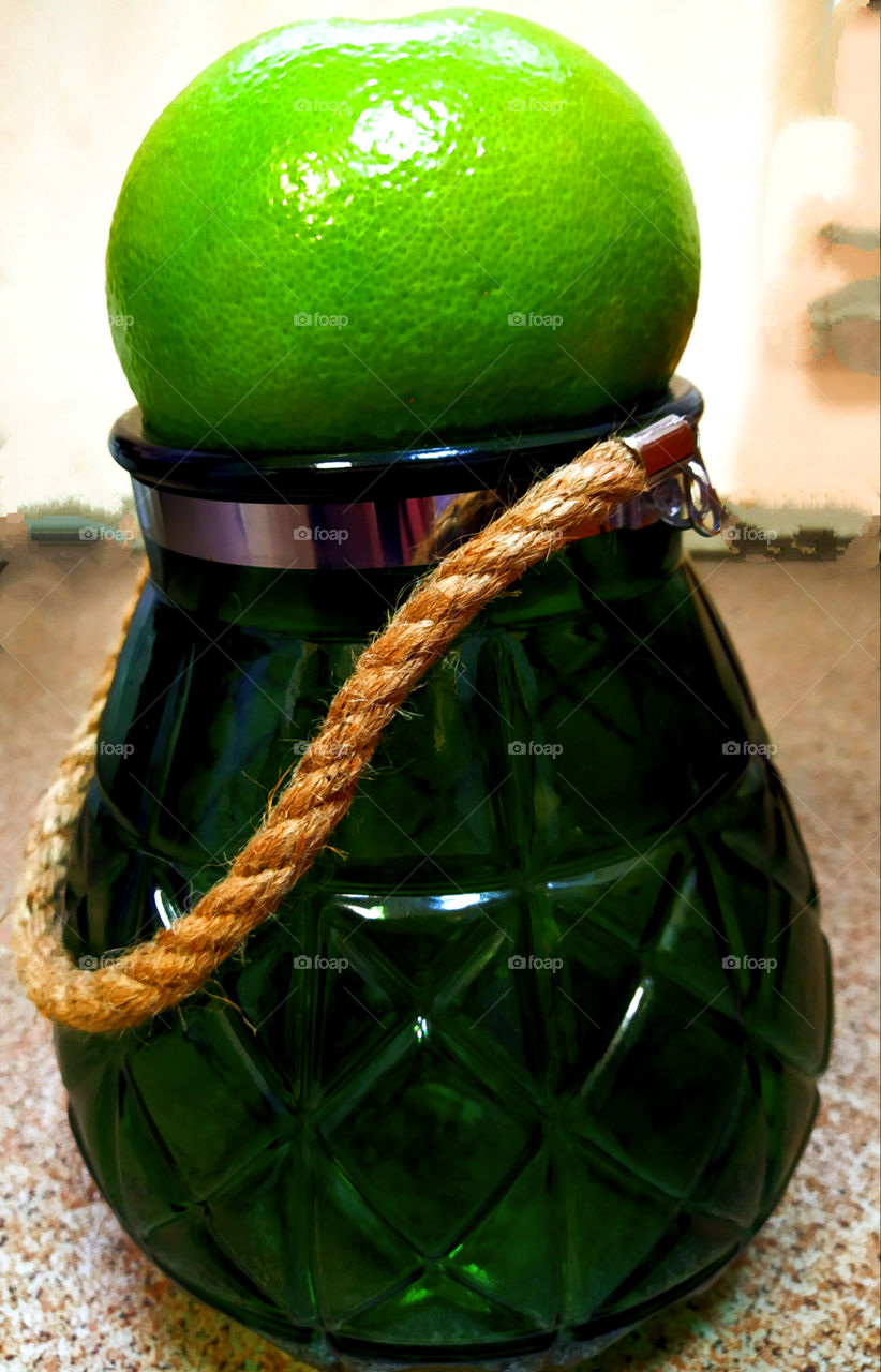 green grapefruit on a green glass vase with a rope handle