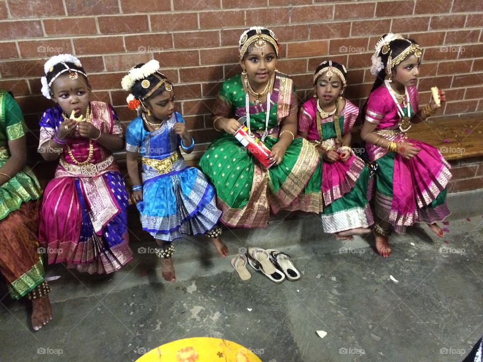 Small girls sitting together near wall in traditional dress