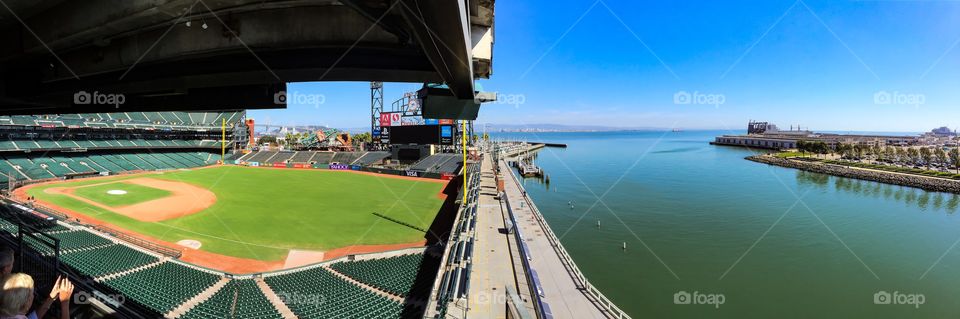 Panorama of AT&T Park at noon. San Francisco, Ca. Home of the San Francisco Giants. Splash landing.  McCovey Cove and the right field wall included as well as the San Francisco/Oakland Bay bridge.  USS Somerset LPD-25 is also in the foreground over left field.