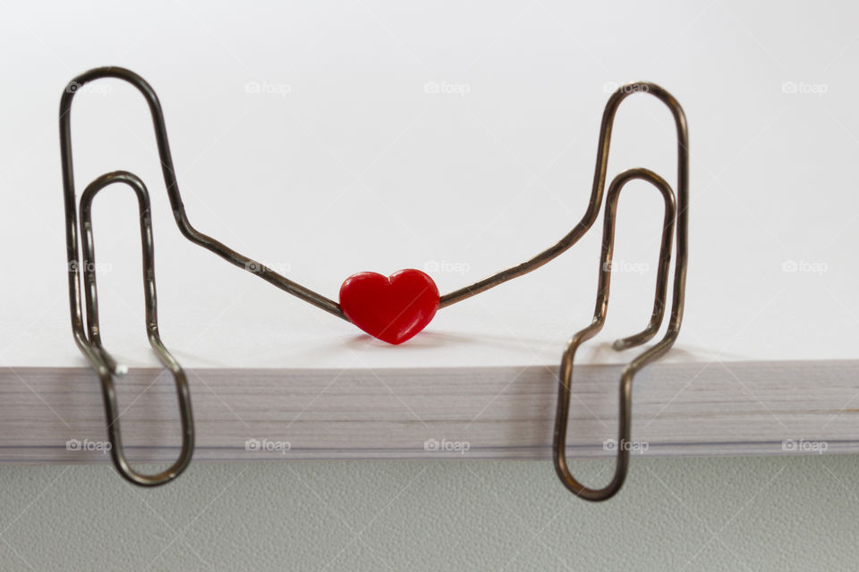 paper clips with heart symbolizing a person sitting on a stack of white paper. love concept