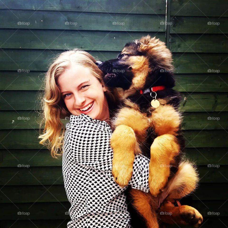 Woman holding a big German shepherd puppy