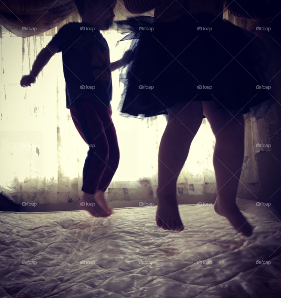 Boy and girl jumping on a bed caught in mid air 