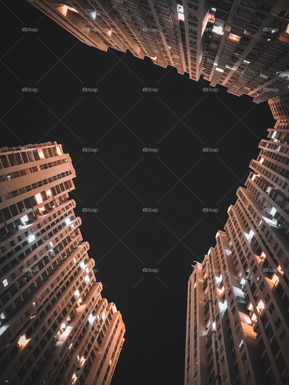 Lights on of the interesting shape of the upper part of the apartment building at night.