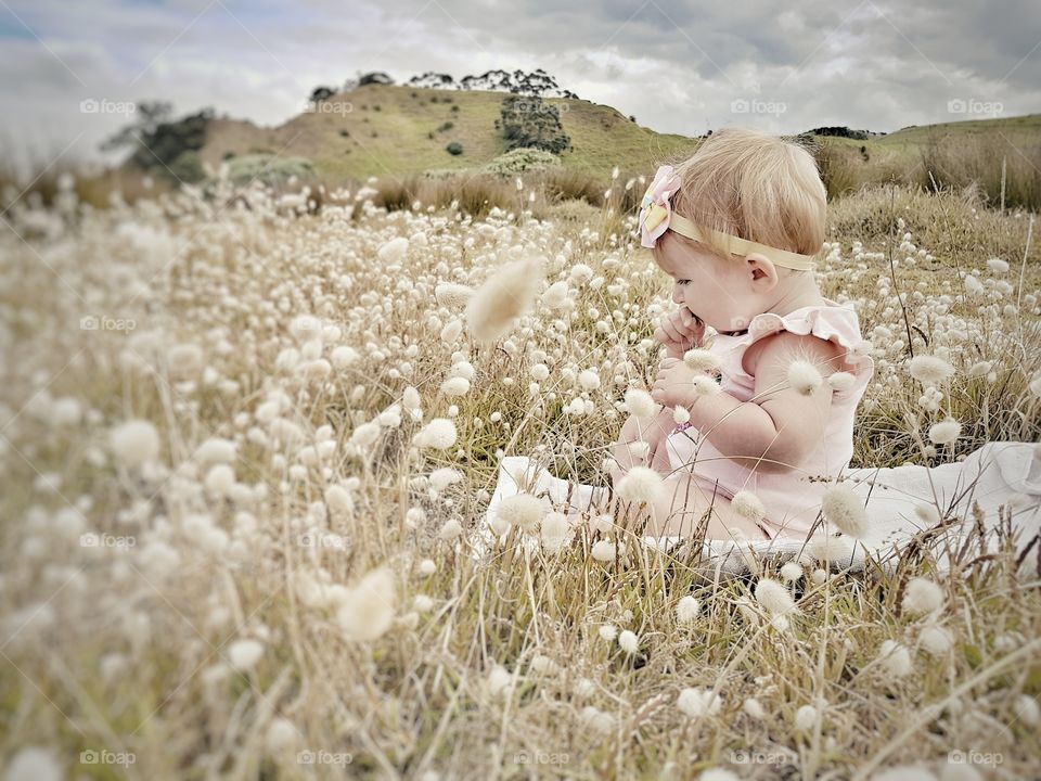 Baby Girl Sitting Playing in field