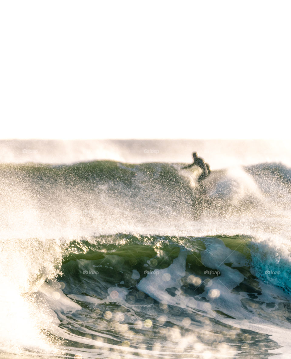 Winter surfing in the cold Atlantic Ocean, with spray coming off the top of large waves. 