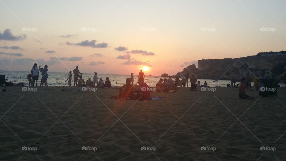 people enjoying themselves on the beach at sunset