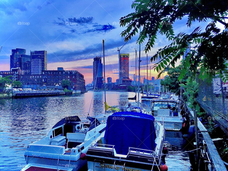 The “harbor area” of Newtown Creek in LIC, Queens, NY in the twilight hour of upcoming nightfall: The setting sun’s last glowing red rays are reflected in the smooth as glass surface of the waters of the East River. 2019. Hypnotic Productions