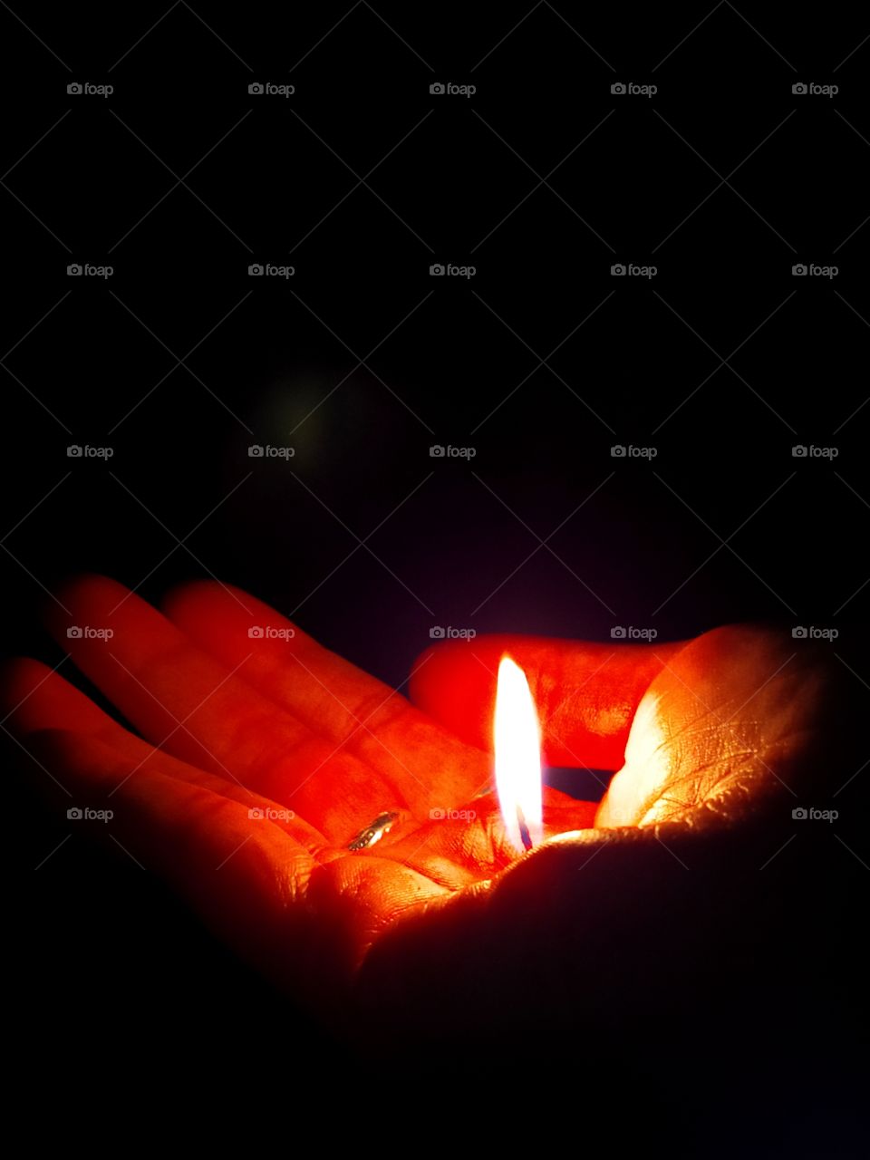Woman's hand holding a small flame of fire