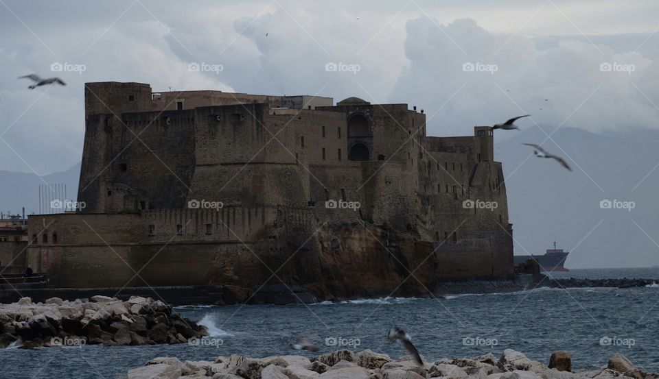 The sun is setting over Castel Dell'Ovo, the Egg Castle in which foundation Virgil allegedly put a magical egg, the only thing that still supports its fortification and protects the city of Naples