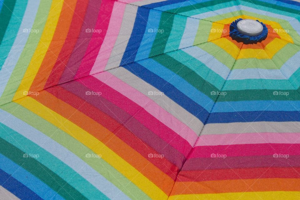 A closeup view of the top of a multi colored umbrella.