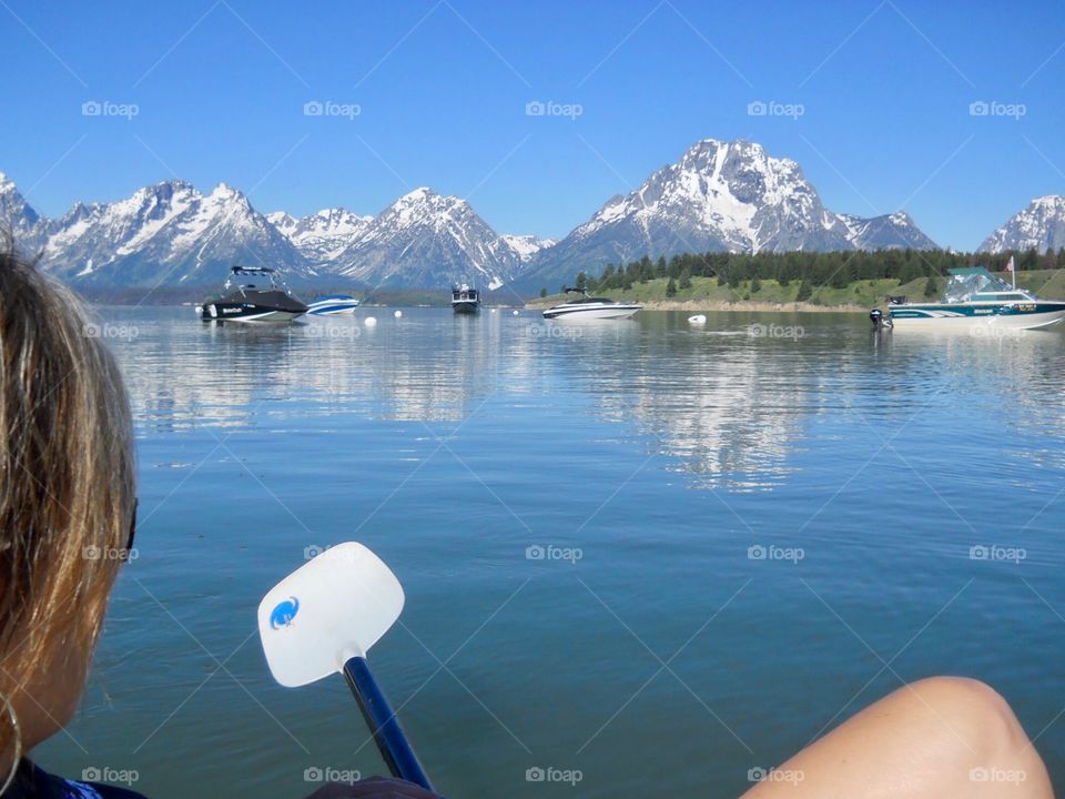 Woman on kayak over looking Grand Tetons