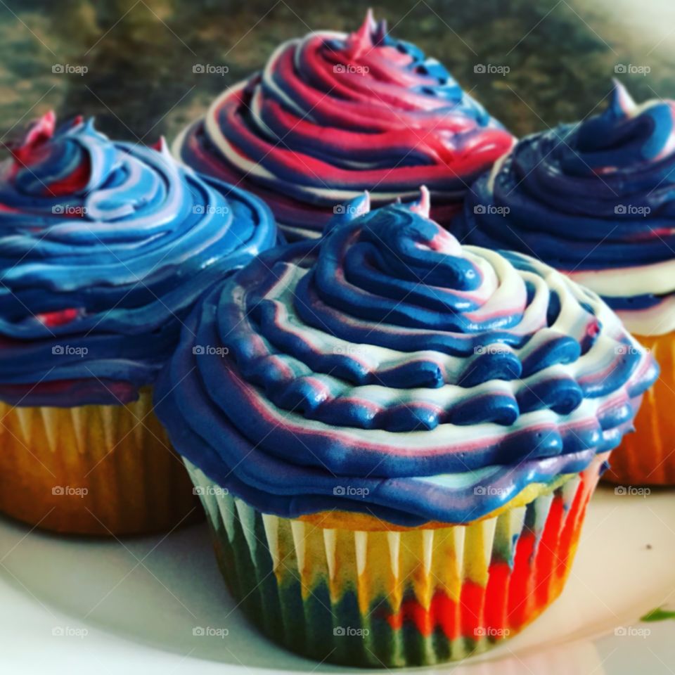 4 Red, white, blue cupcakes with red, white, and blue swirled frosting sitting on a plate
