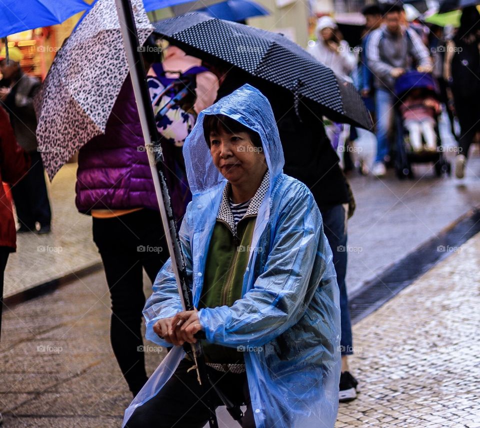 Woman Patiently Waiting  at the Middle of the busy Road while raining. 