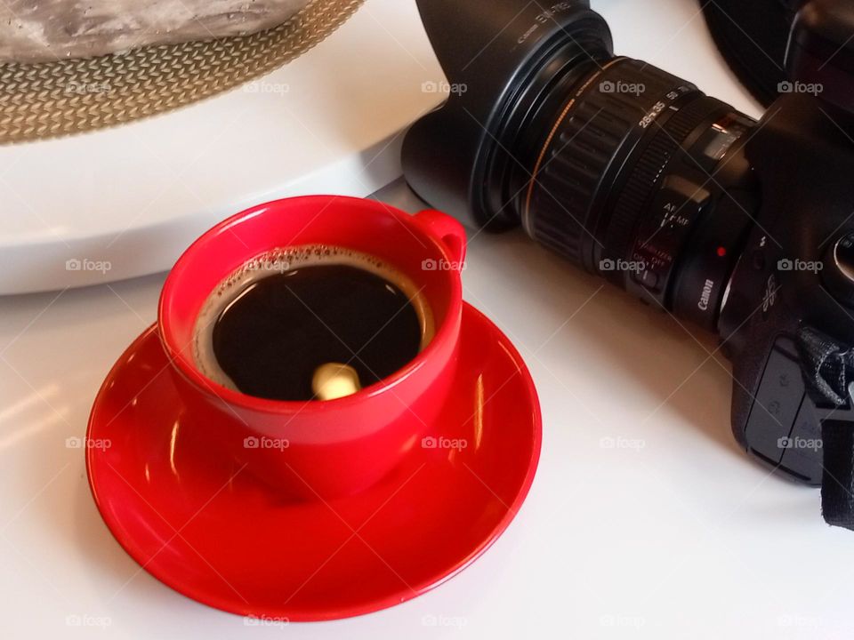 freshly brewed hot coffee in a red cup and a dslr